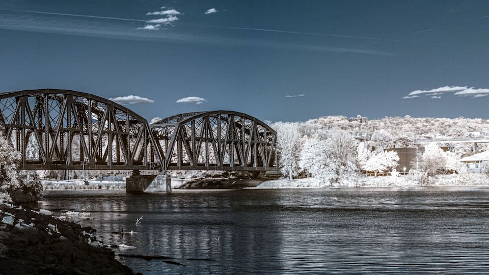 A bridge over a river with snow-covered trees and a clear sky.