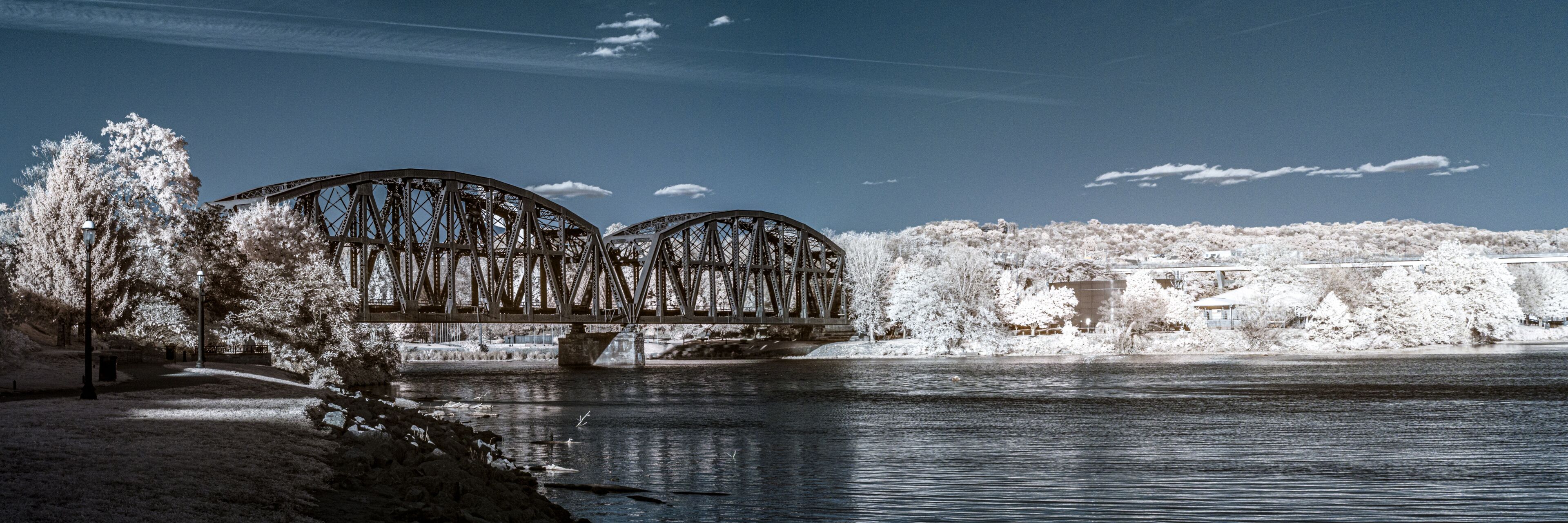 A bridge over a river with snow-covered trees and a clear sky.