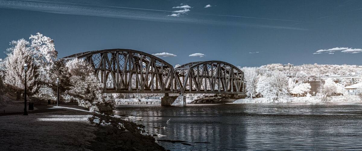 A bridge over a river with snow-covered trees and a clear sky.