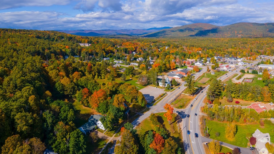 An aerial view of a town surrounded by autumn-colored forests and mountains.