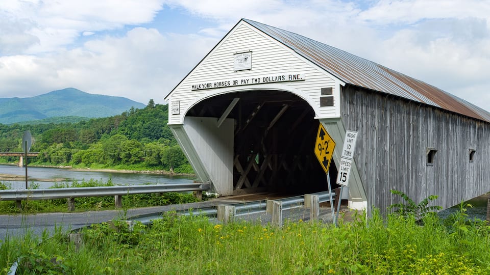 A covered bridge with a sign that says "Walk your horses or pay two dollars fine."