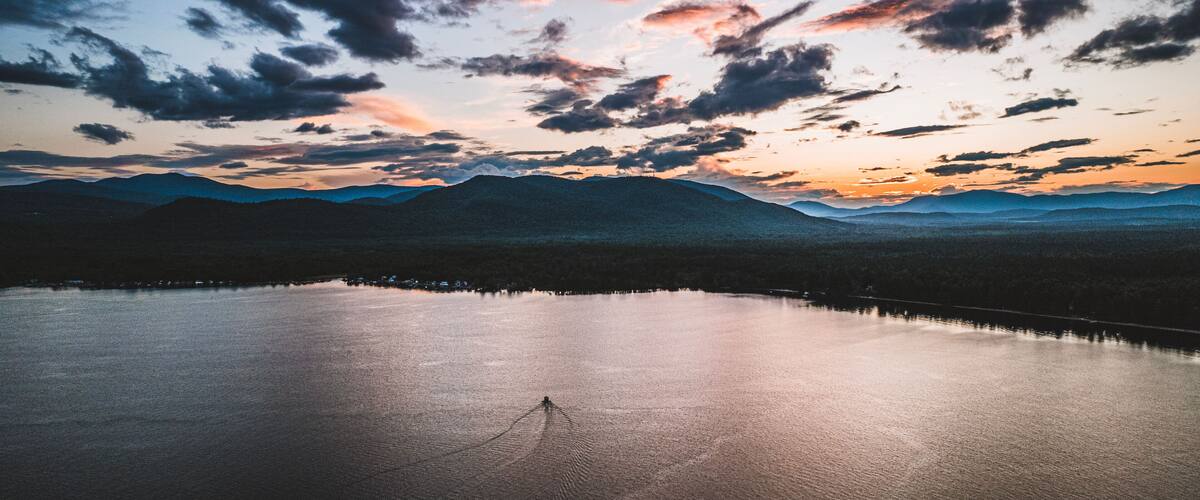 A calm lake with mountains in the background and a sunset sky.