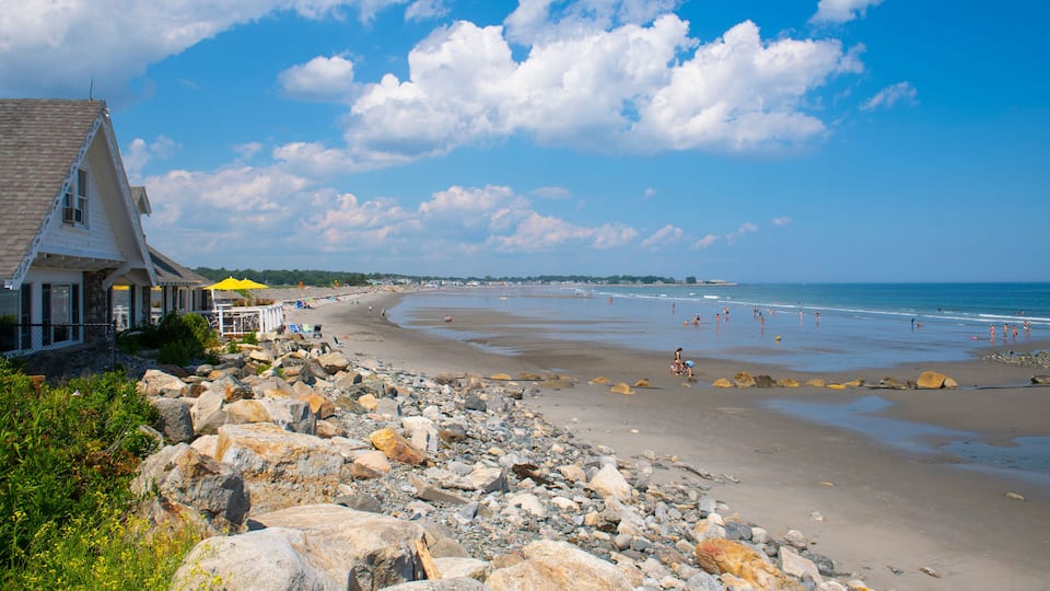 A rocky beach with a building and a yellow umbrella.