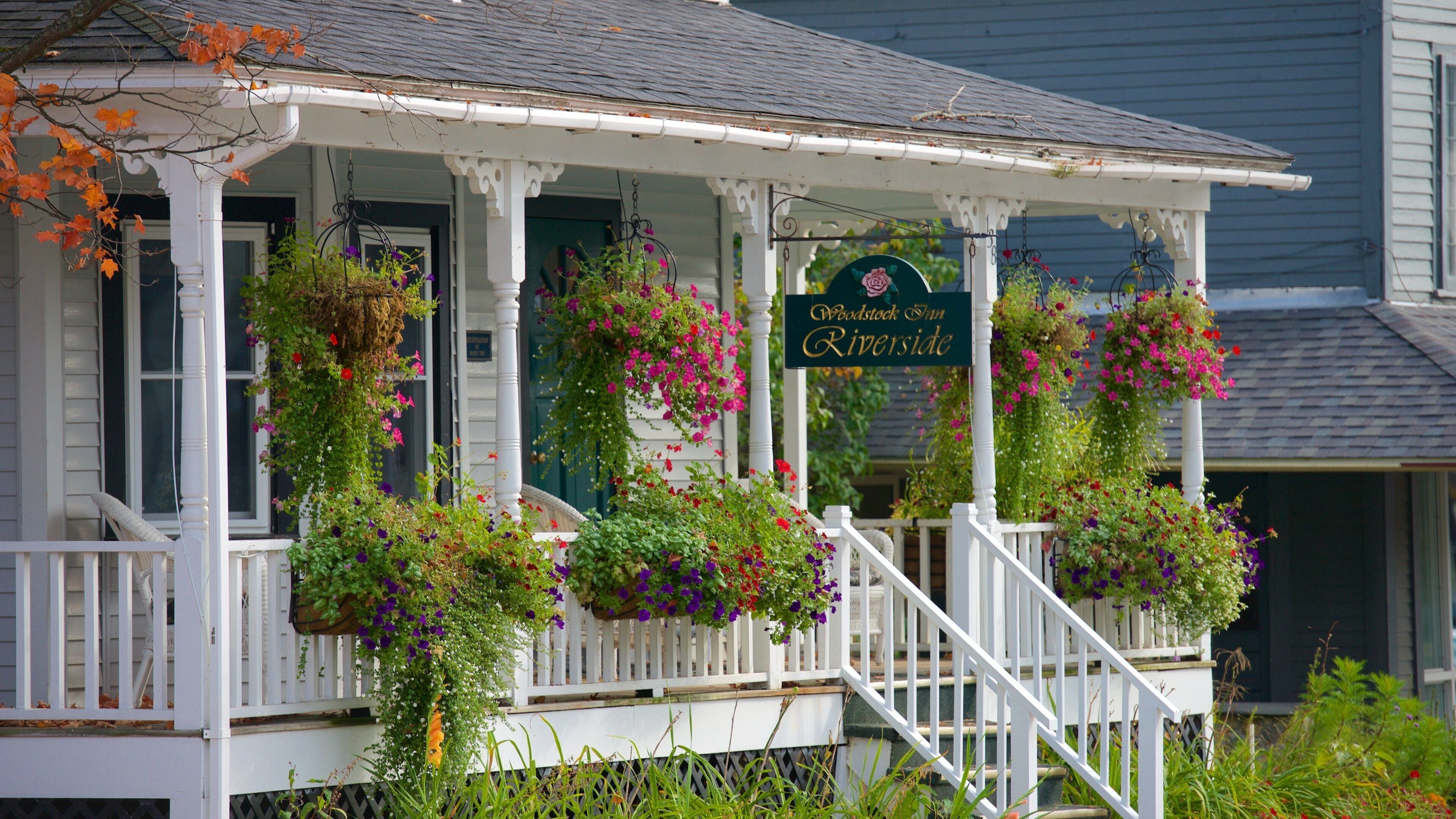 A porch with hanging flower baskets and a sign that reads "Woodstock Inn Riverside."