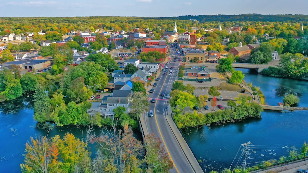 Une ville traversée par une rivière, avec un pont et le clocher d’une église.
