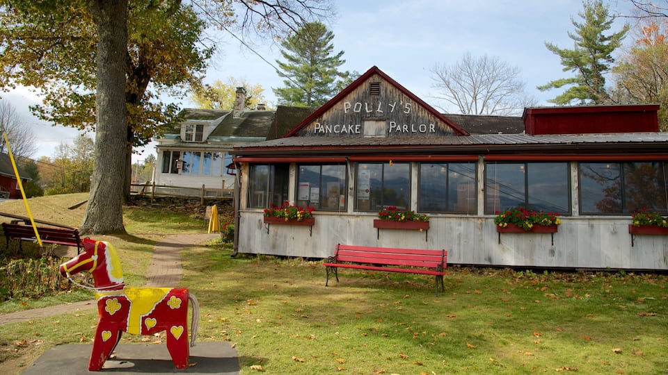 A rustic building with a sign reading "Polly's Pancake Parlor" and a red bench in front.