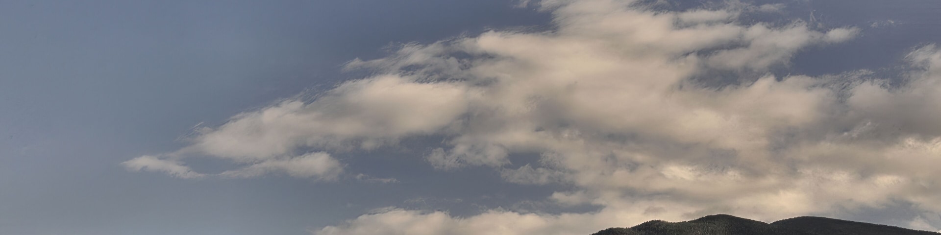 A mountain range with autumn foliage and a crescent moon in the sky.