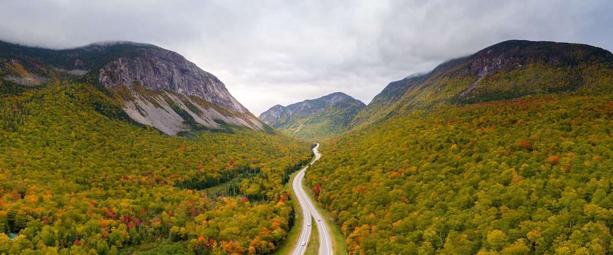 A winding road through a mountainous forest with autumn foliage.