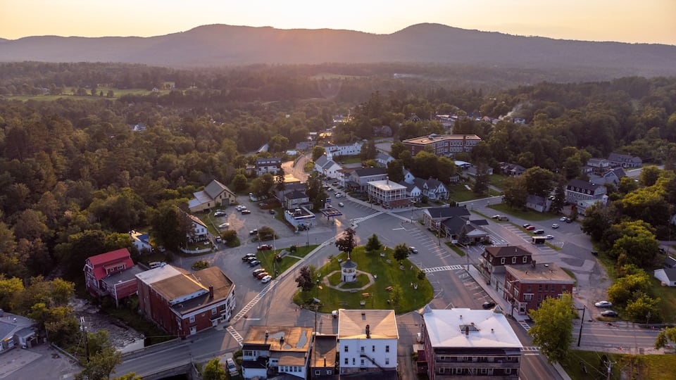 A town with a central roundabout, surrounded by residential and commercial buildings, with hills in the background.
