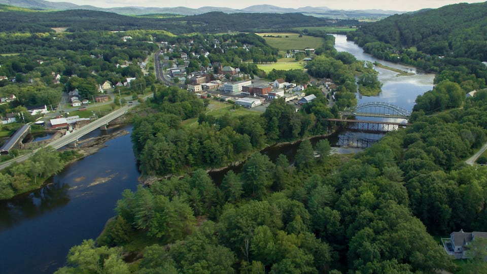 A river flowing through a town surrounded by dense forests and hills.