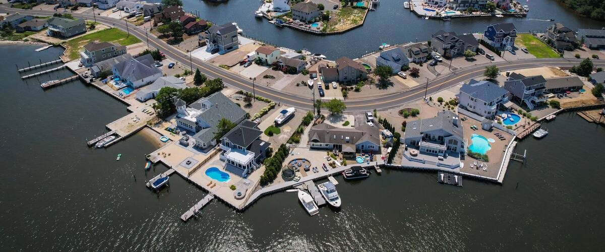 An aerial view of a coastal residential area with houses, docks, and a marina.