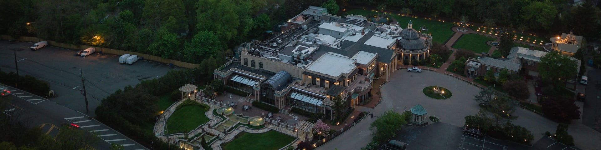 An aerial view of a town with a large building complex surrounded by greenery.