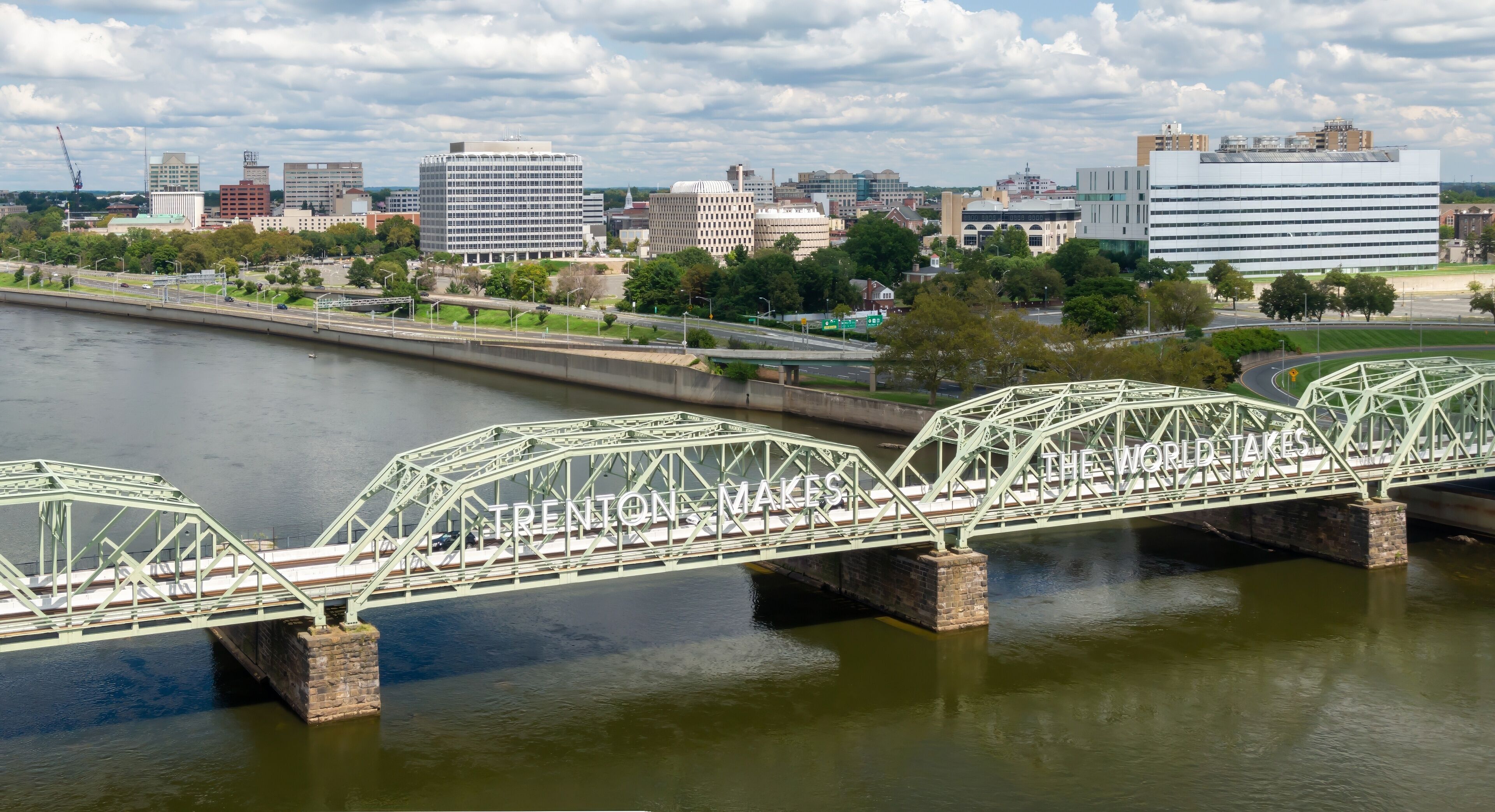 A green steel bridge over a river with the text "TRENTON, MAKES THE WORLD'S" on it.