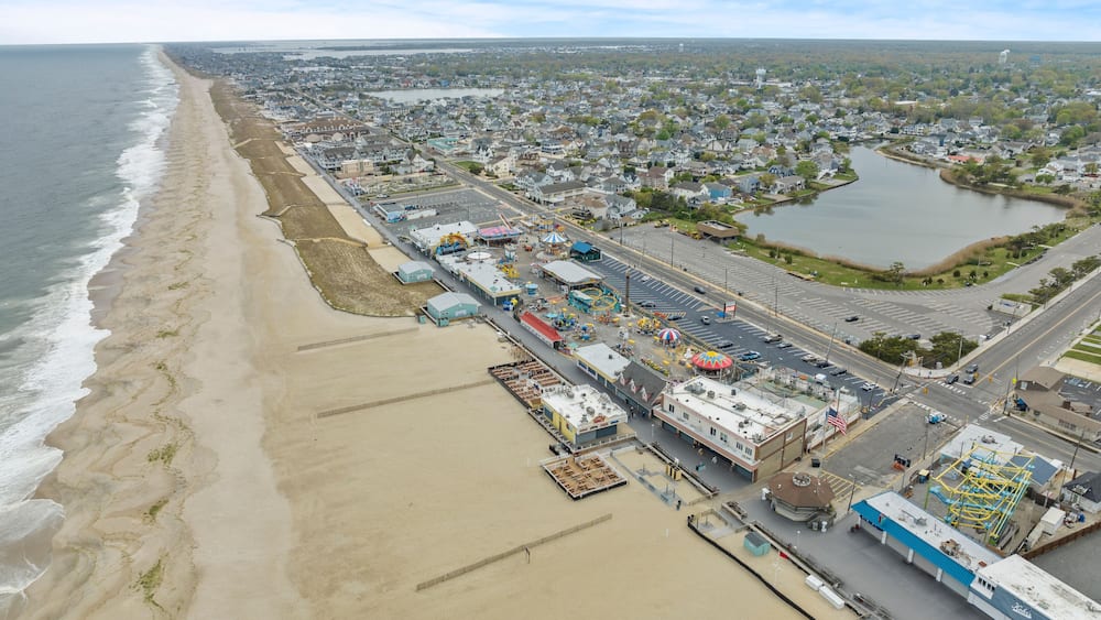 A coastal cityscape with a beach, industrial area, and a large body of water.