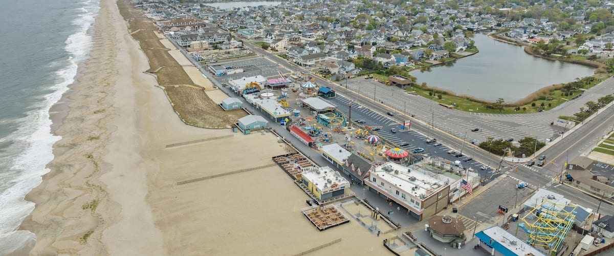 A coastal cityscape with a beach, industrial area, and a large body of water.