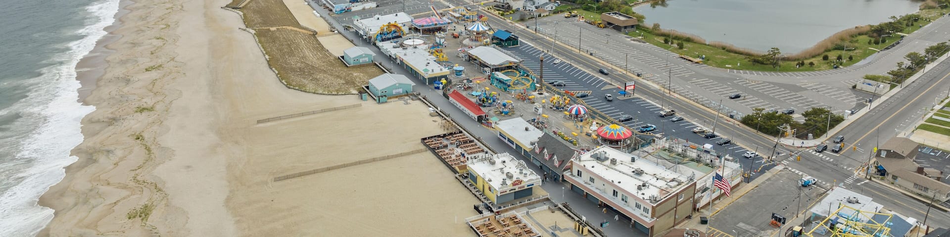 A coastal cityscape with a beach, industrial area, and a large body of water.