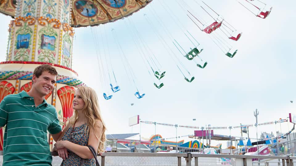A carousel with colorful decorations and a man and woman standing in front.