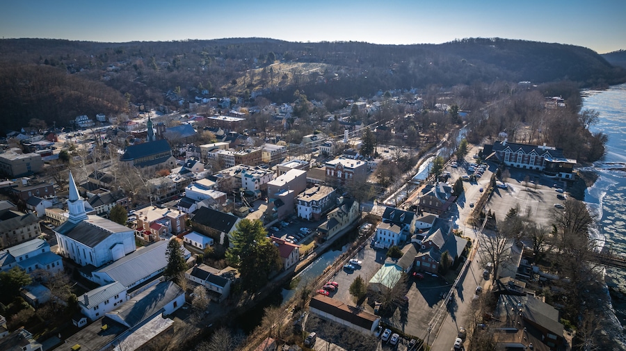 An aerial view of a town with a prominent church, a river, and surrounding hills.