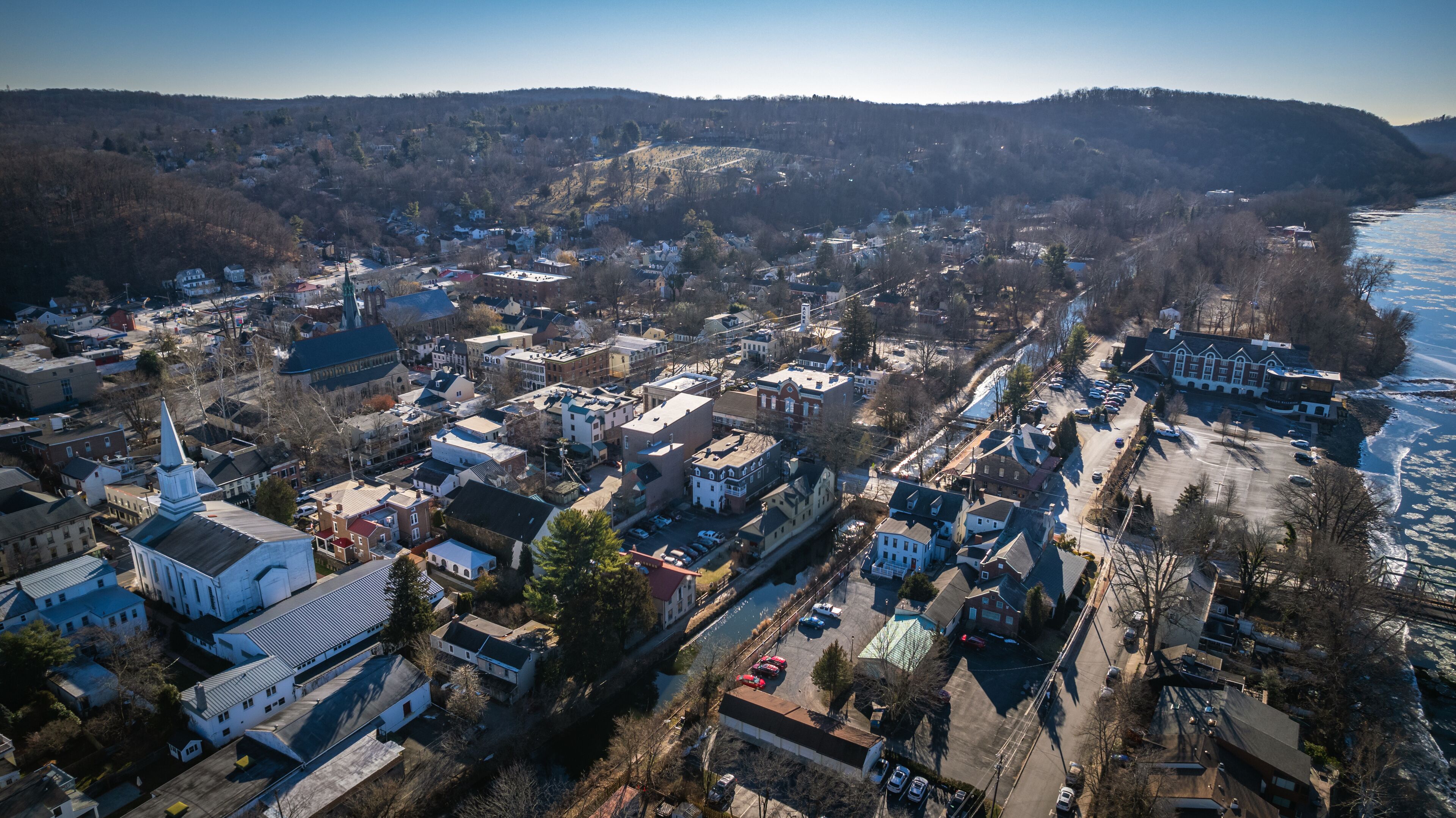 An aerial view of a town with a prominent church, a river, and surrounding hills.