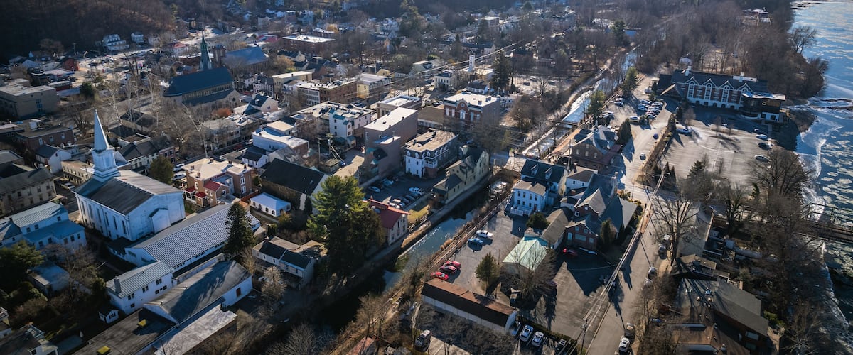 An aerial view of a town with a prominent church, a river, and surrounding hills.