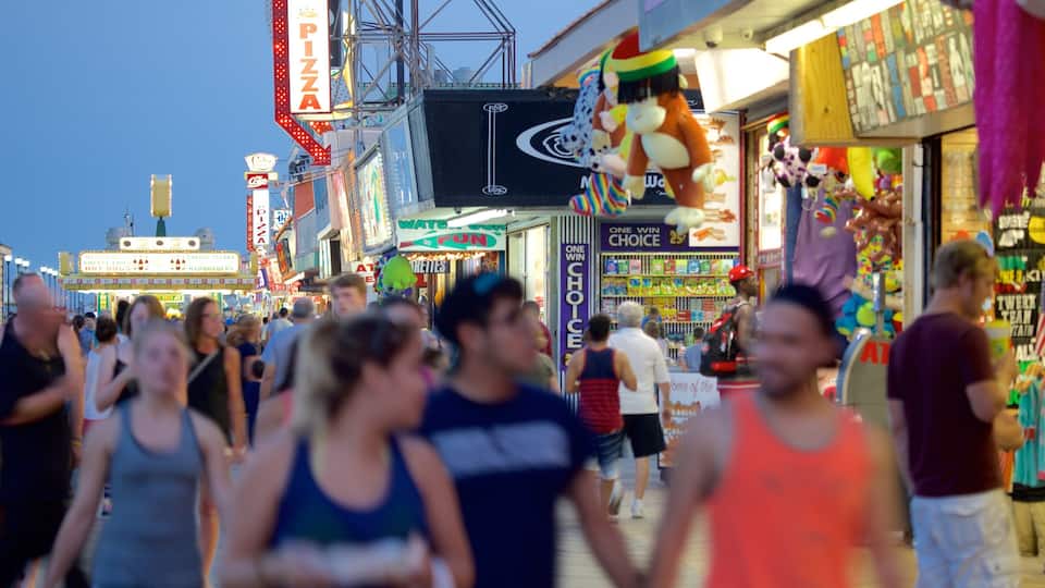 A crowded boardwalk with various shops and a prominent pizza sign.