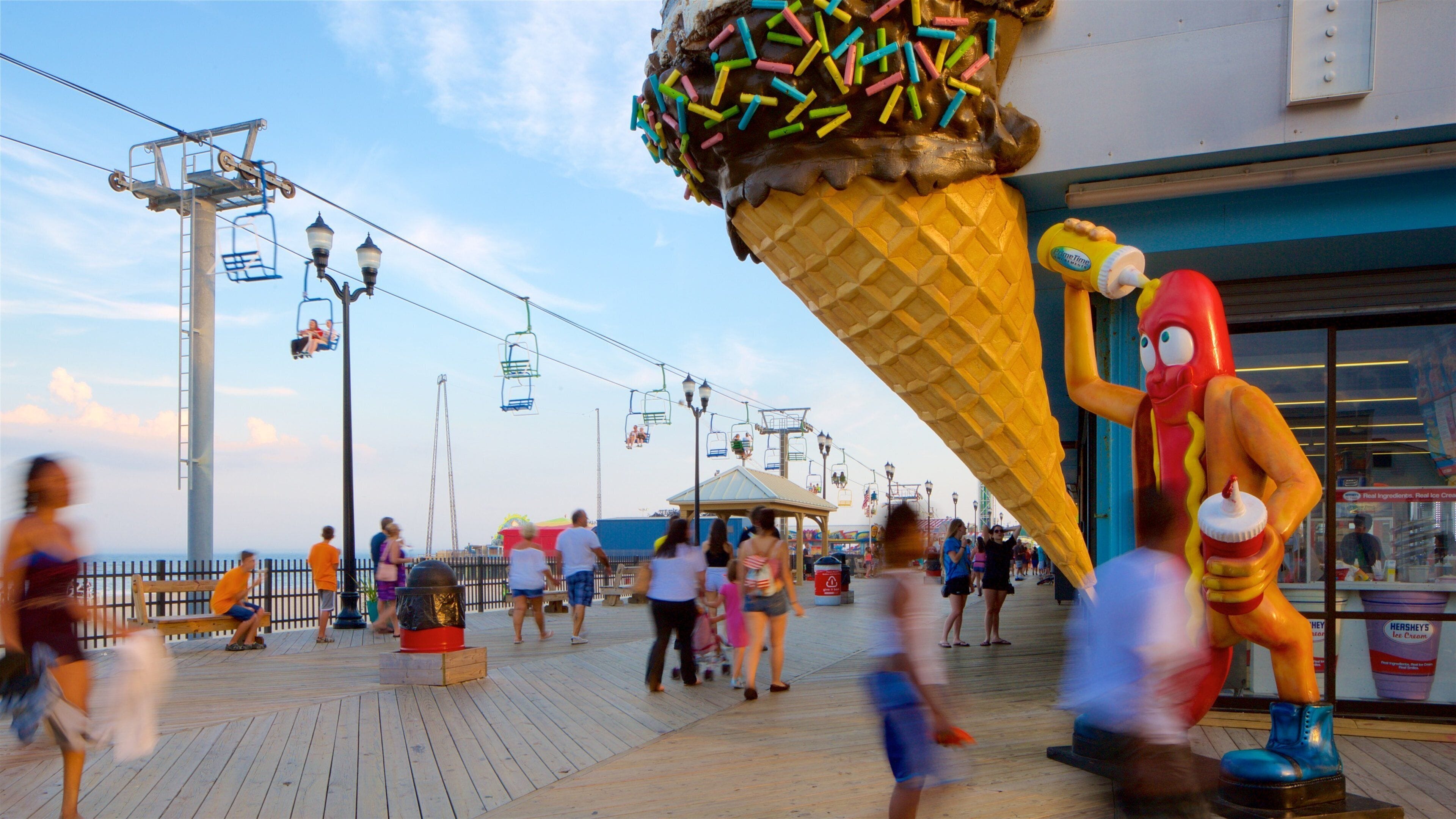 A boardwalk with a large ice cream cone sculpture, a Ferris wheel, and a Hershey's ice cream shop.