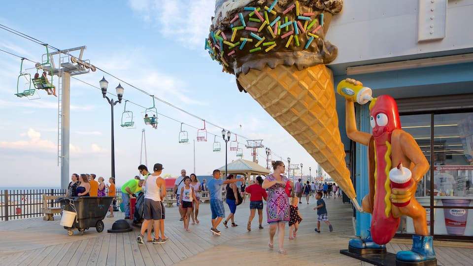 A boardwalk with people, a Ferris wheel, and a large ice cream cone sculpture.