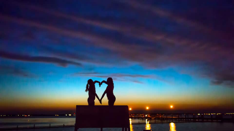 A sunset over a body of water with a pier in the background.