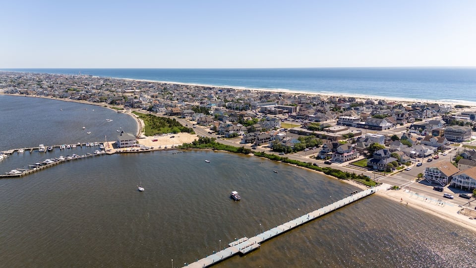 An aerial view of a coastal town with a marina, beach, and residential area.