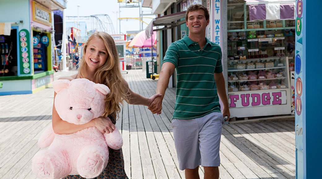 Teenage couple holding hands on boardwalk with teddy bear