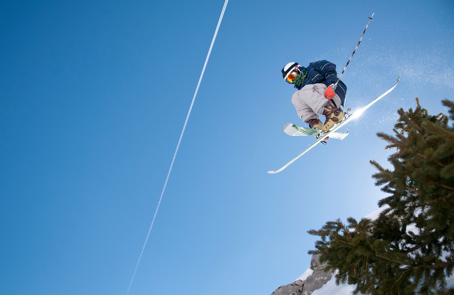 A skier in mid-air against a clear blue sky.
