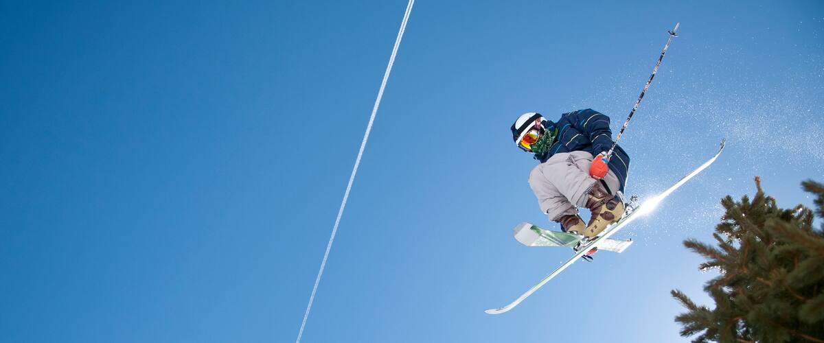 A skier in mid-air against a clear blue sky.
