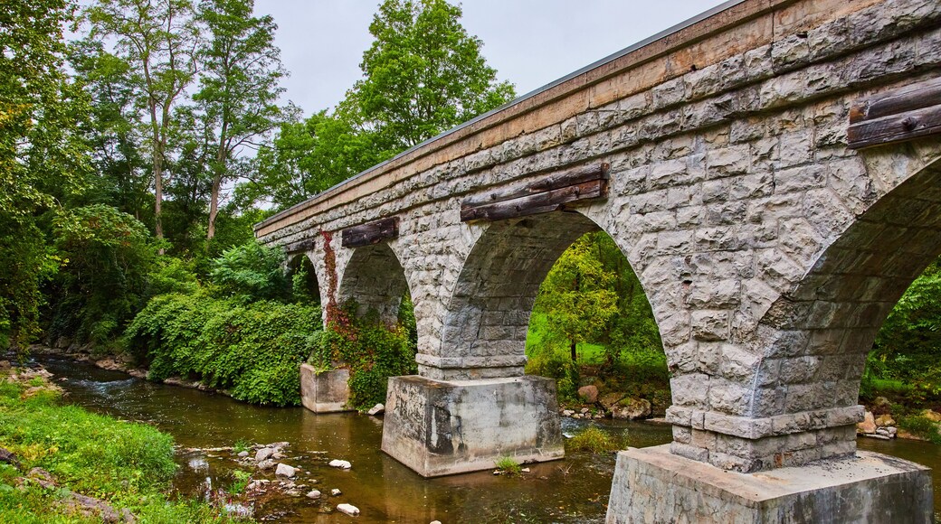 Old stone arch bridge for train tracks over small river