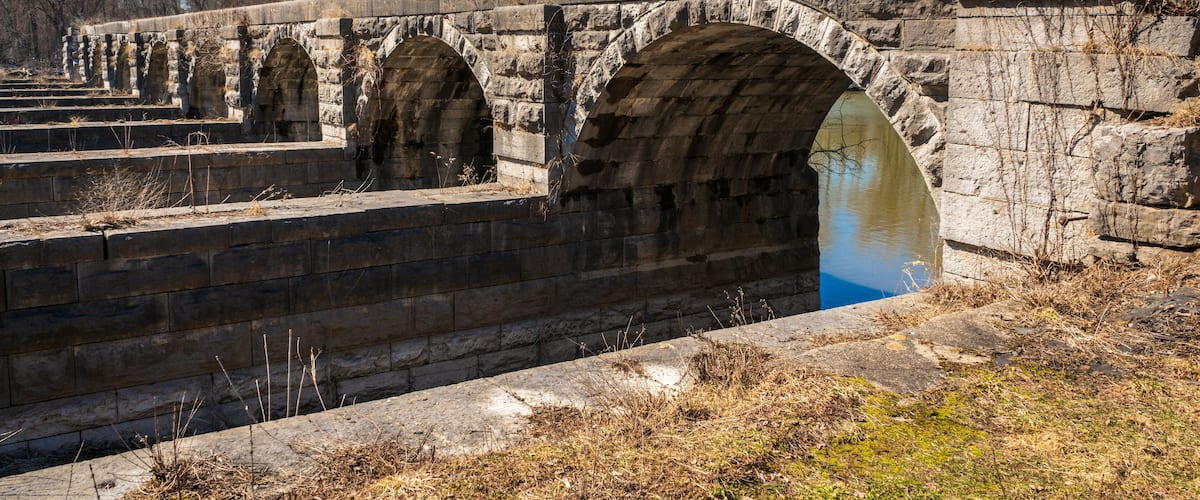 An old stone bridge with multiple arches over a canal.