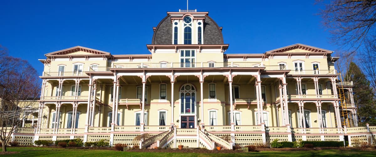 A large, historic building with a central dome, multiple balconies, and a flagpole.