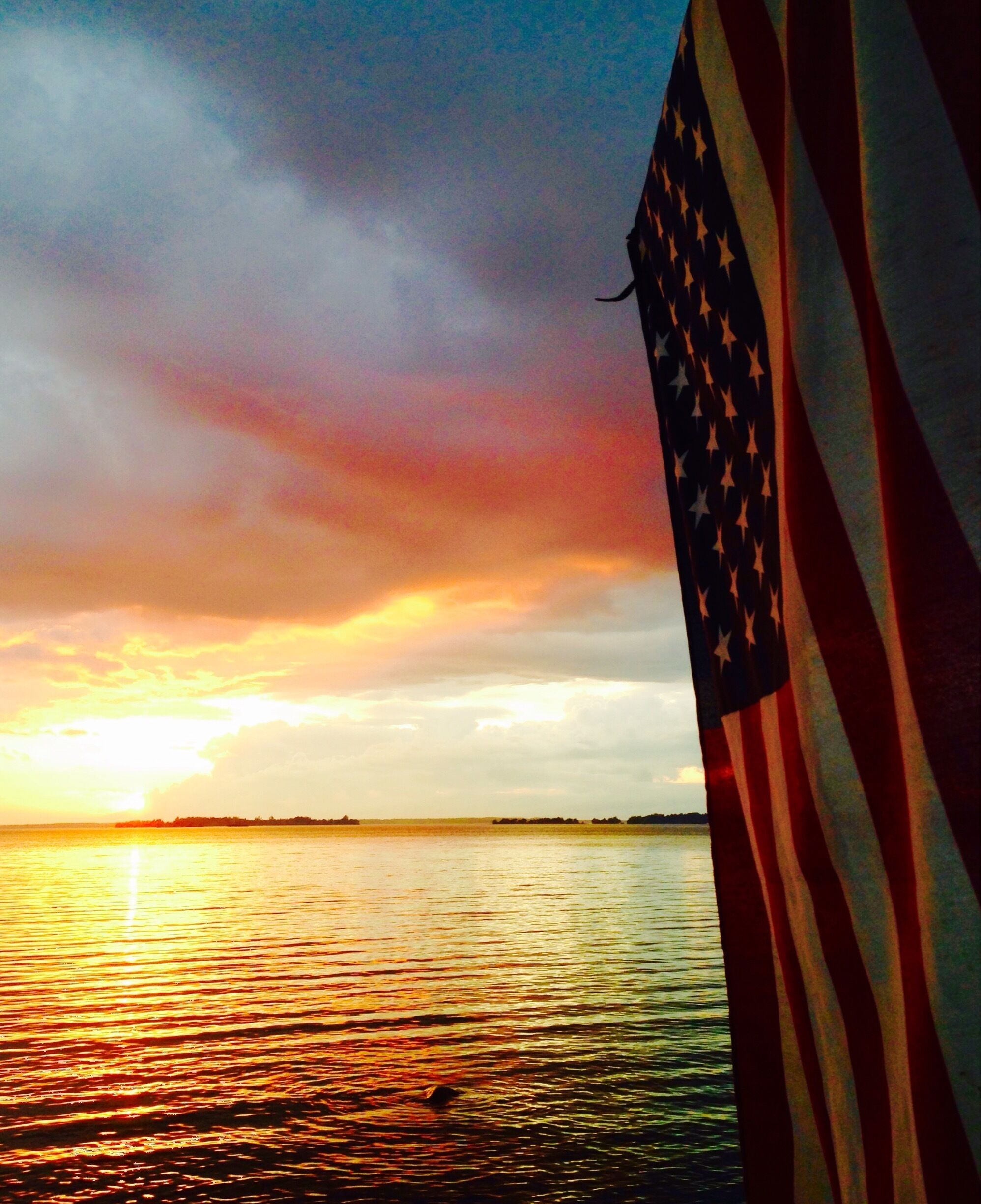 Sunset over Saint Lawrence River from the United States side in Clayton, NY. The American Flag is hung over a piece of drift wood with the name Joe Morabito, who was killed in action June 8th, 2013. (My dad)  #goldenhour 