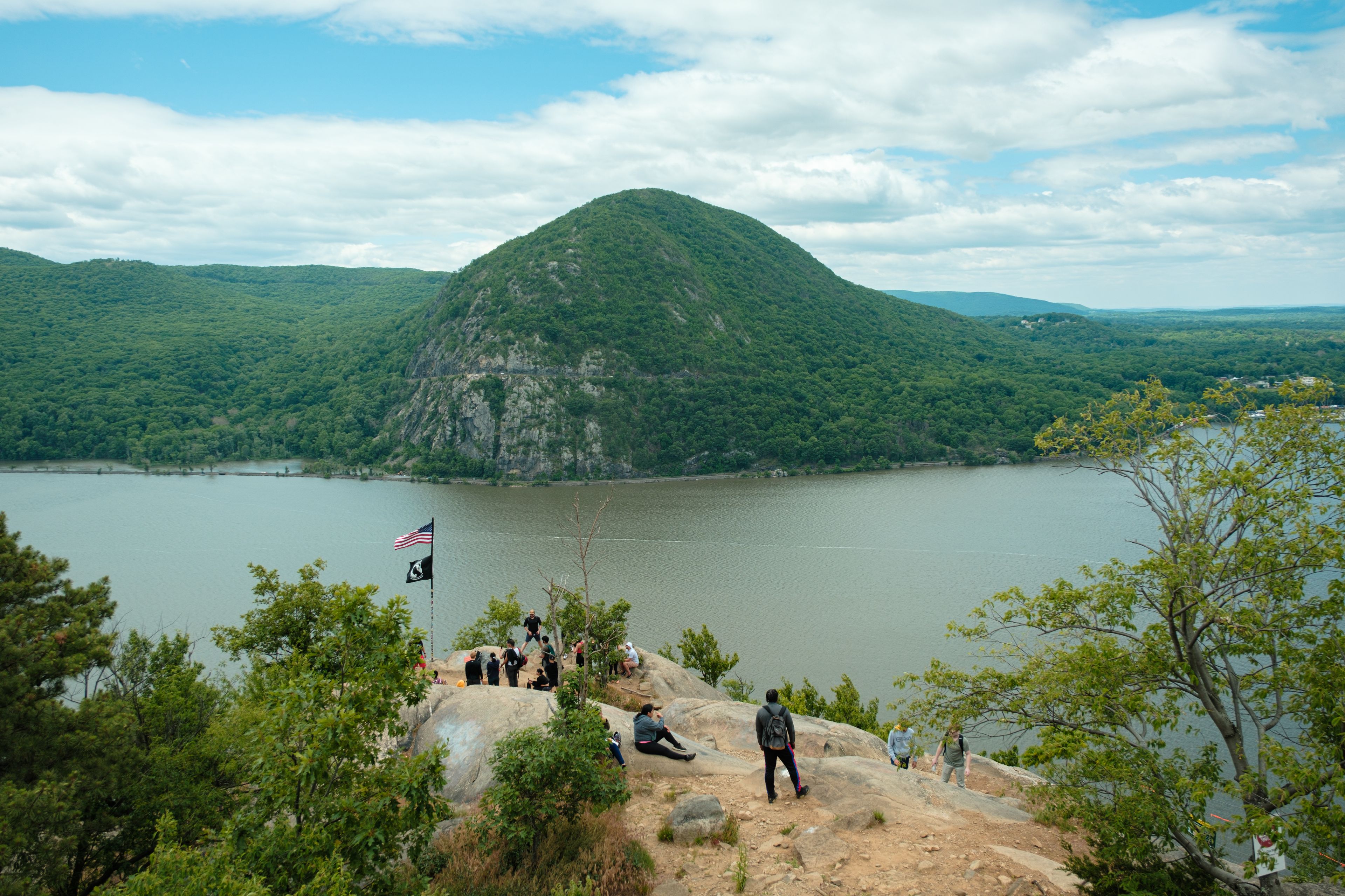 A group of people on a rocky outcrop overlooking a lake with a mountain in the background.