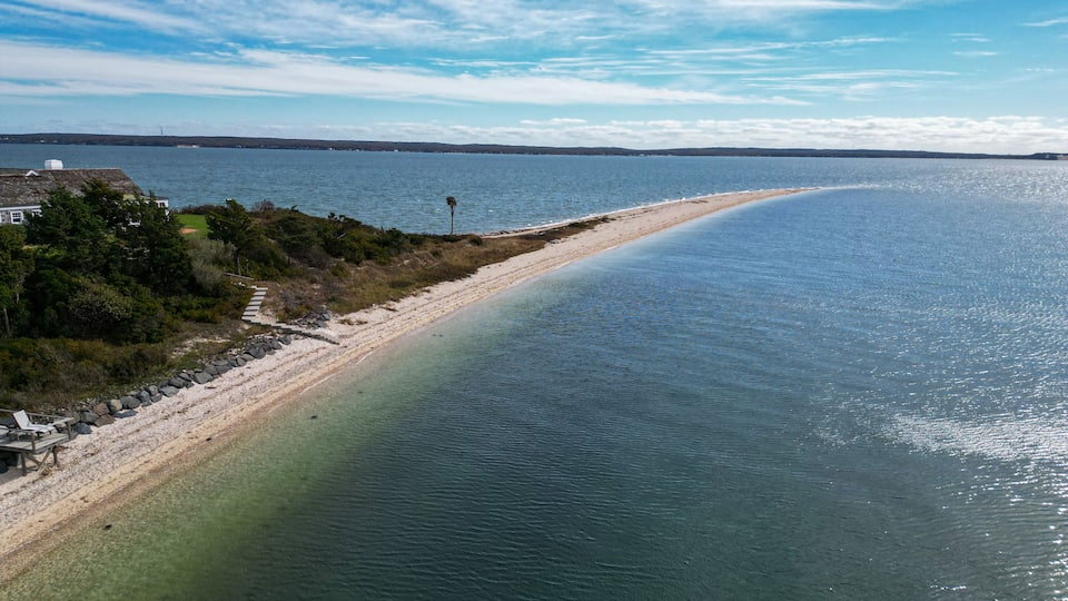 A coastal landscape with a sandy beach, calm waters, and a clear sky.