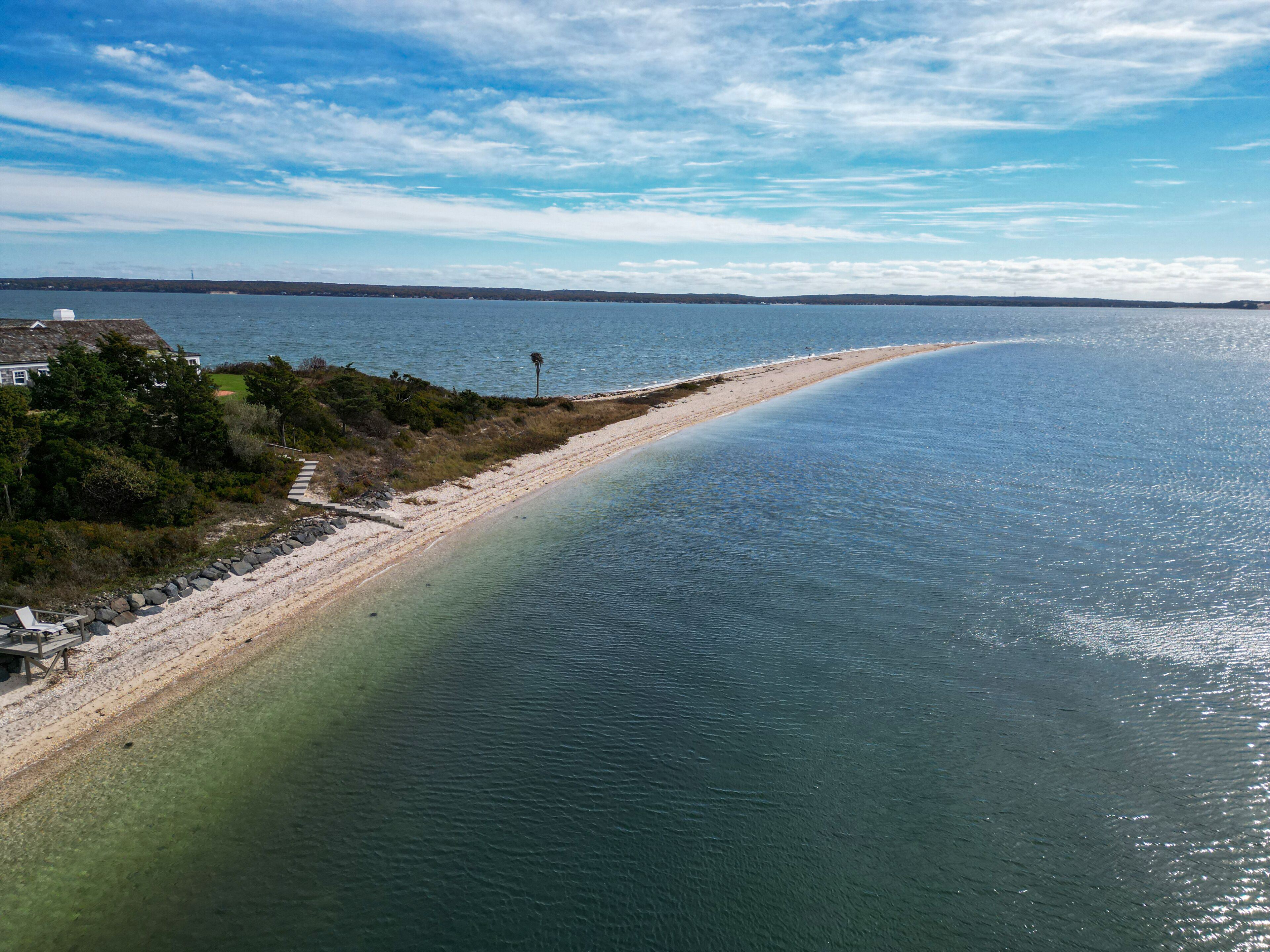 A coastal landscape with a sandy beach, calm waters, and a clear sky.