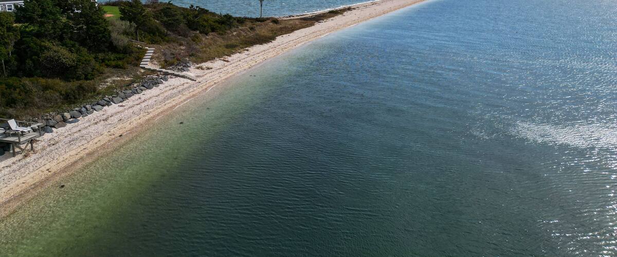 A coastal landscape with a sandy beach, calm waters, and a clear sky.