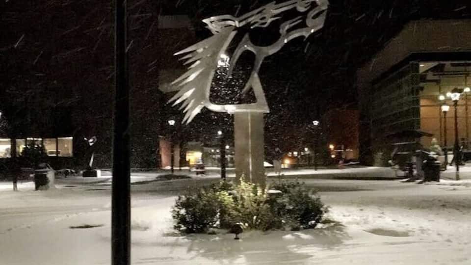 A snow-covered outdoor area with a street lamp and a metal sculpture.