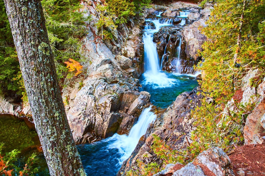 Stunning serene cascading blue waterfalls into buckets along rocky canyon with forest around