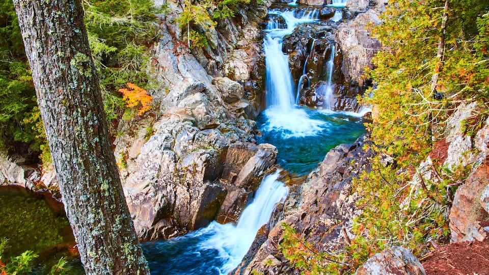 Stunning serene cascading blue waterfalls into buckets along rocky canyon with forest around