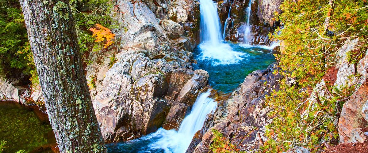 A waterfall cascading over rocks surrounded by trees and foliage.