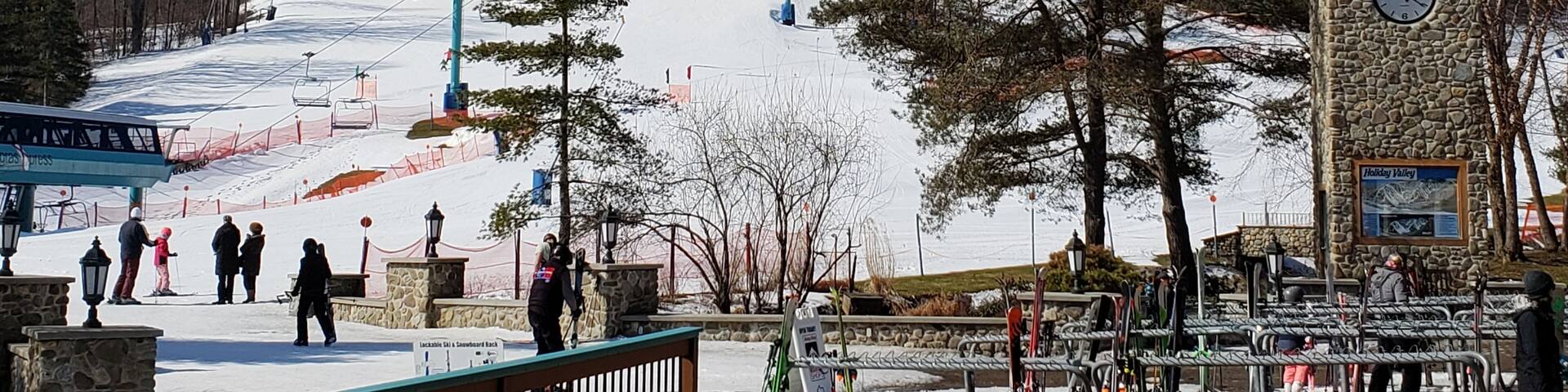 A ski resort with a ski lift, a clock tower, and a sign for Holiday Valley.