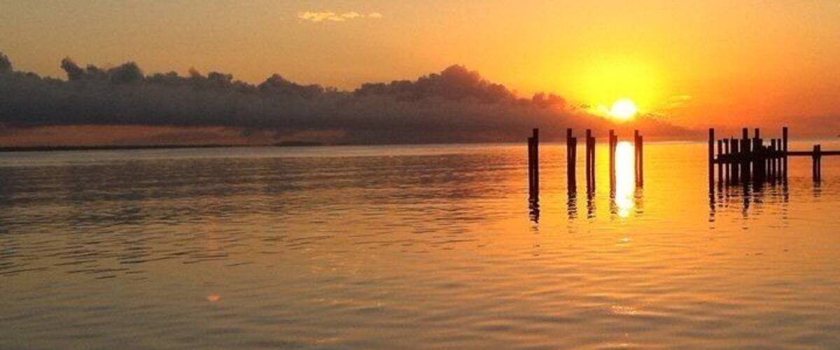 A sunset over a calm lake with wooden docks extending into the water.
