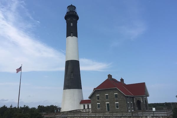 Un grand phare, avec un bâtiment à toit rouge à côté.