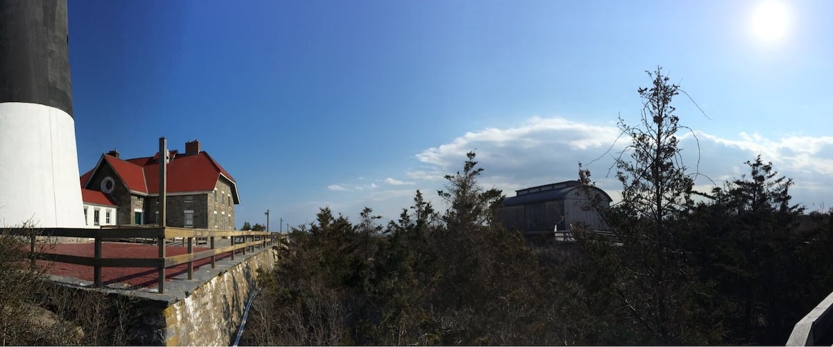 A lighthouse, a red-roofed building, and a wooden structure near a coastal area.