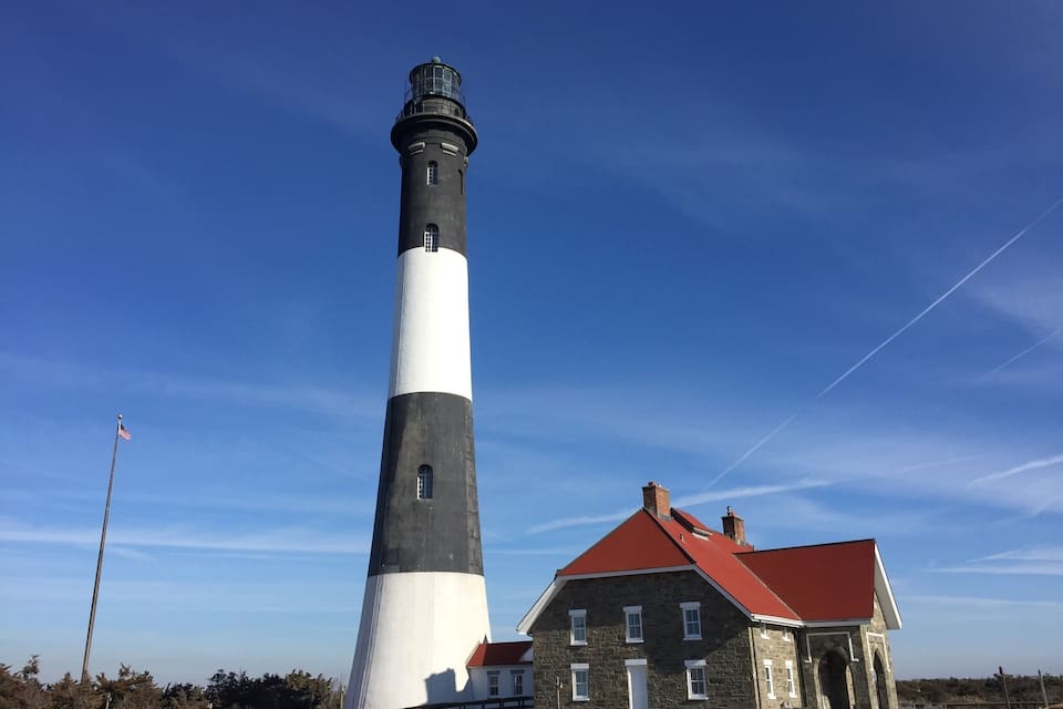 Un faro con una torre bianco e nera accanto a un edificio in pietra con tetto rosso.