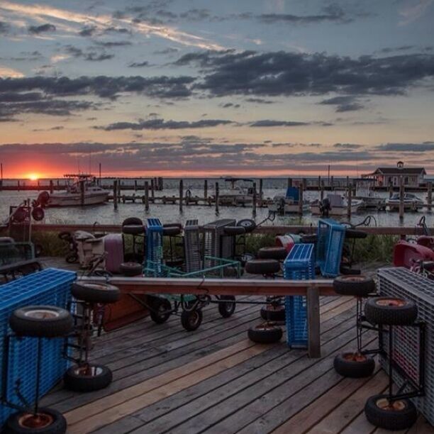 A wooden pier with tires and crates, overlooking a sunset over the water.